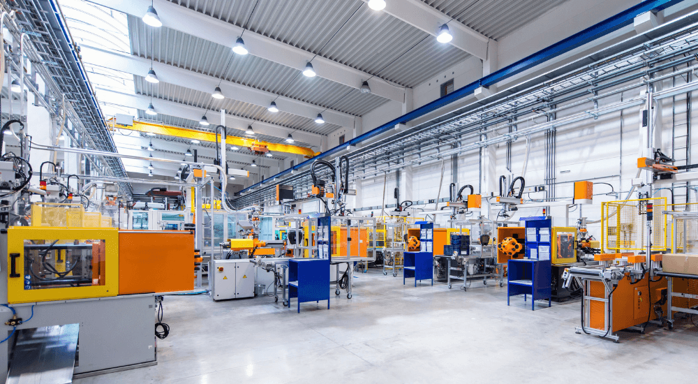 Large modern factory with robots and machines producing industrial plastic pieces and equipment.